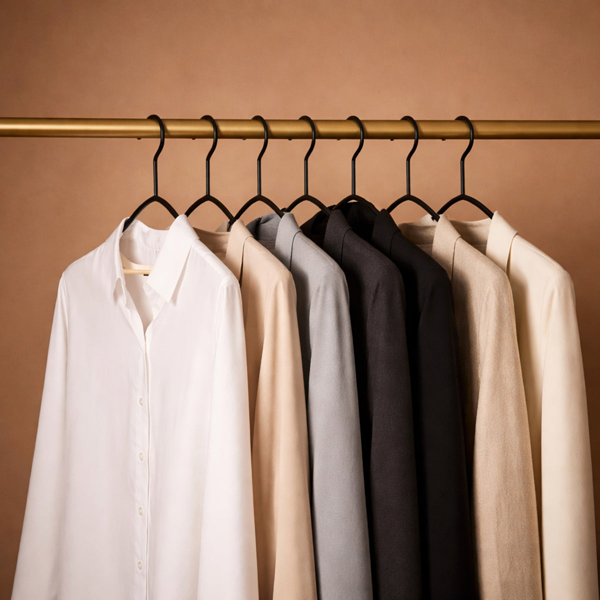 Varios ganchos negros instalados sosteniendo diferentes prendas de ropa demostrando su capacidad de carga y orden en el closet
